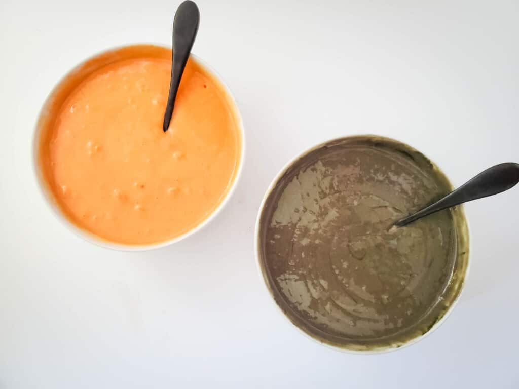 one bowl of black cake batter, and a small bowl of orange cake batter