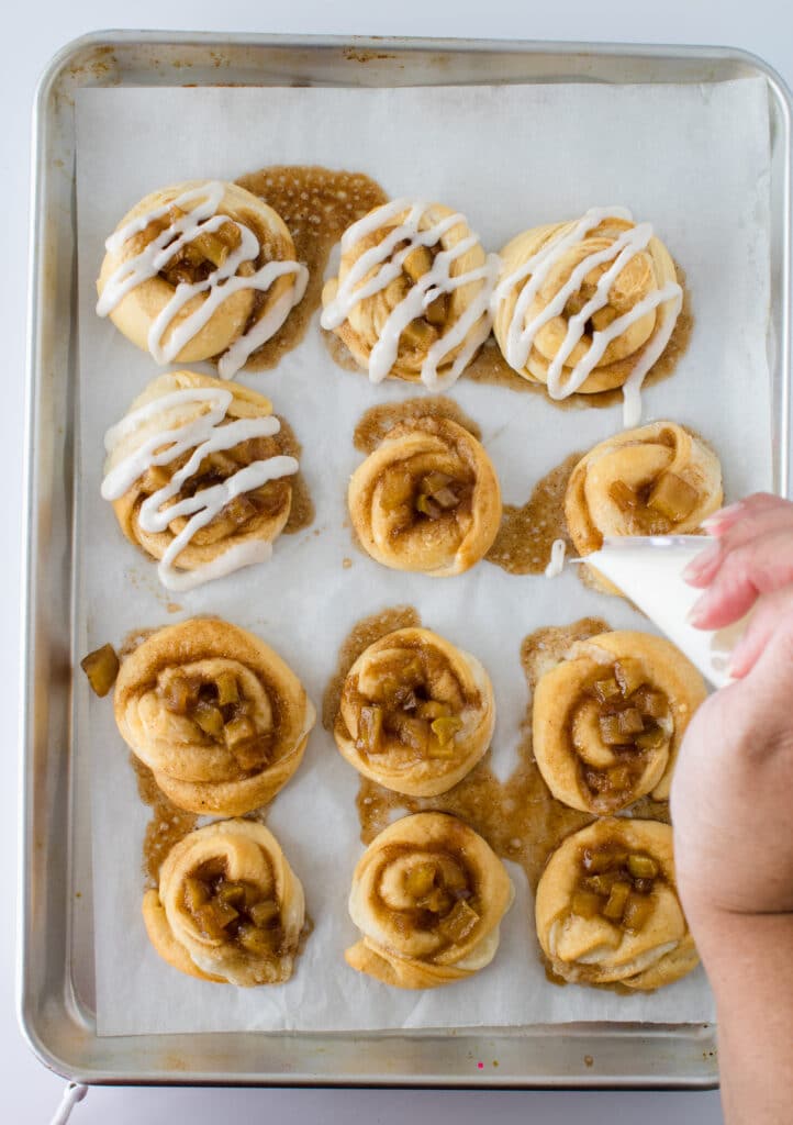 danishes on baking sheet with woman squeezing icing on them