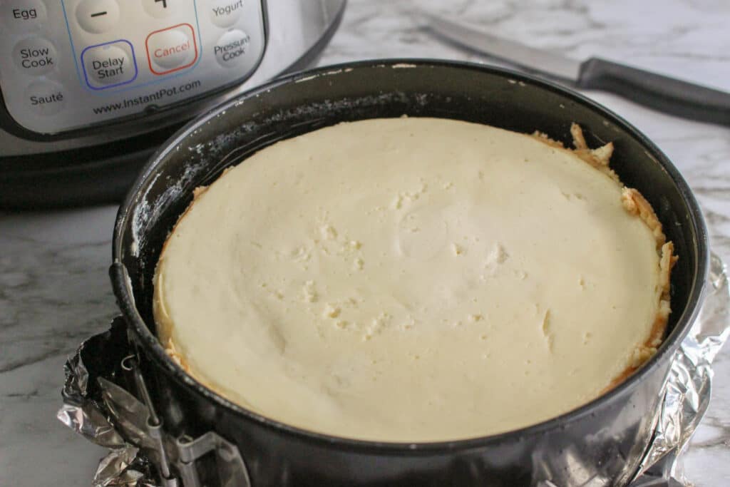 finished sugar cookie cheesecake in a spring form pan with an instant pot in the background.
