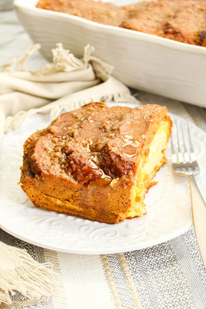 side view of a slice of pumpkin french toast casserole on a white plate with a fork