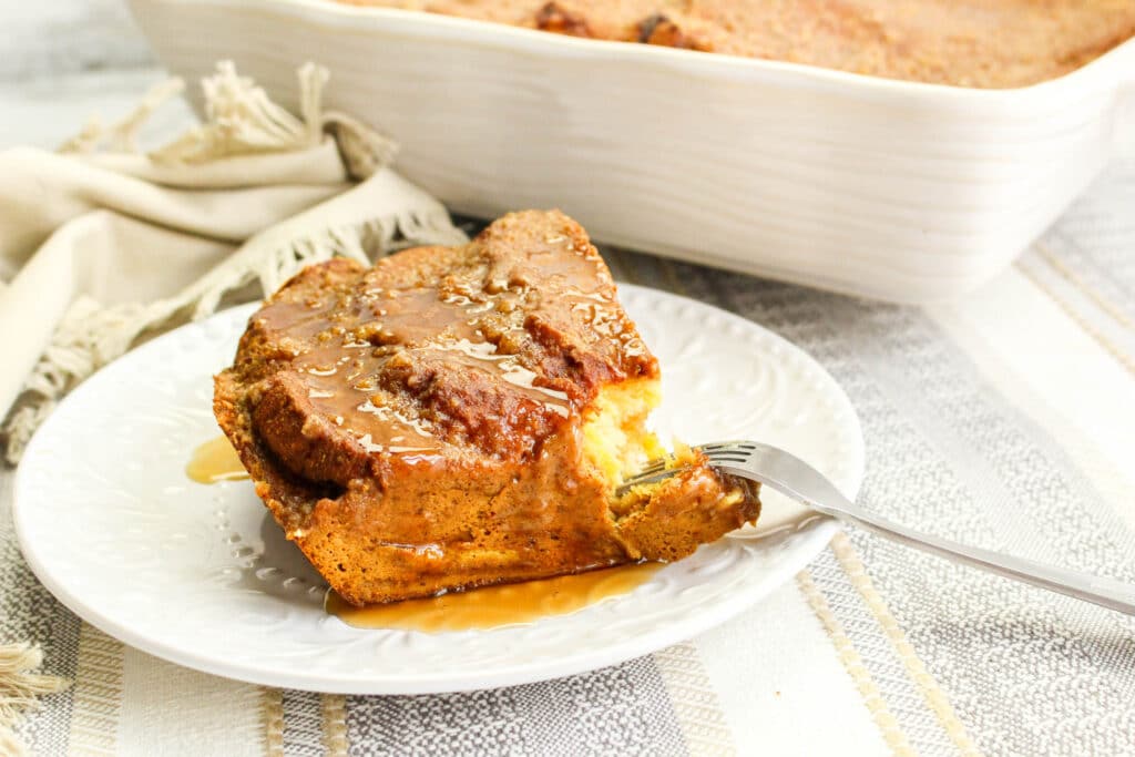 slice of Pumpkin French Toast Casserole on a white plate with a bite missing
