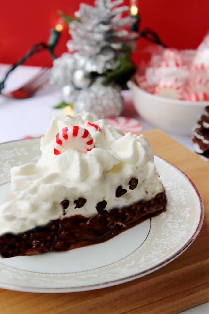 Candy Cane Pie on a white plate with a bowl of peppermints in the background