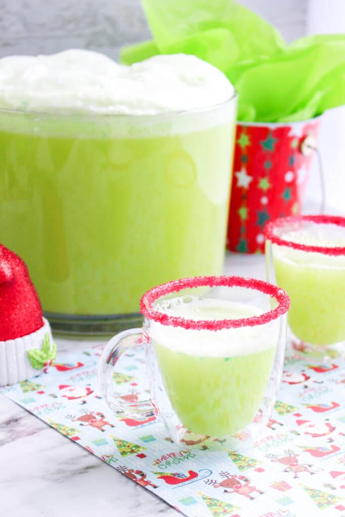 off center image of a glass mug that is rimmed in red sanding sugar and filled with grinch punch