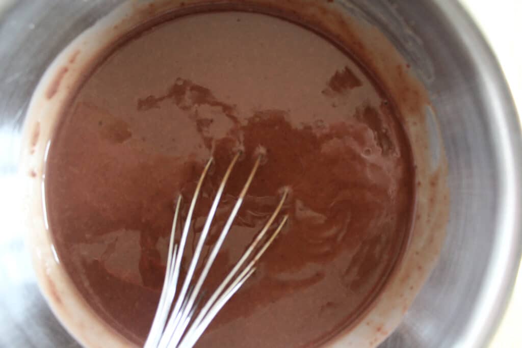 chocolate pudding being whisked in metal bowl