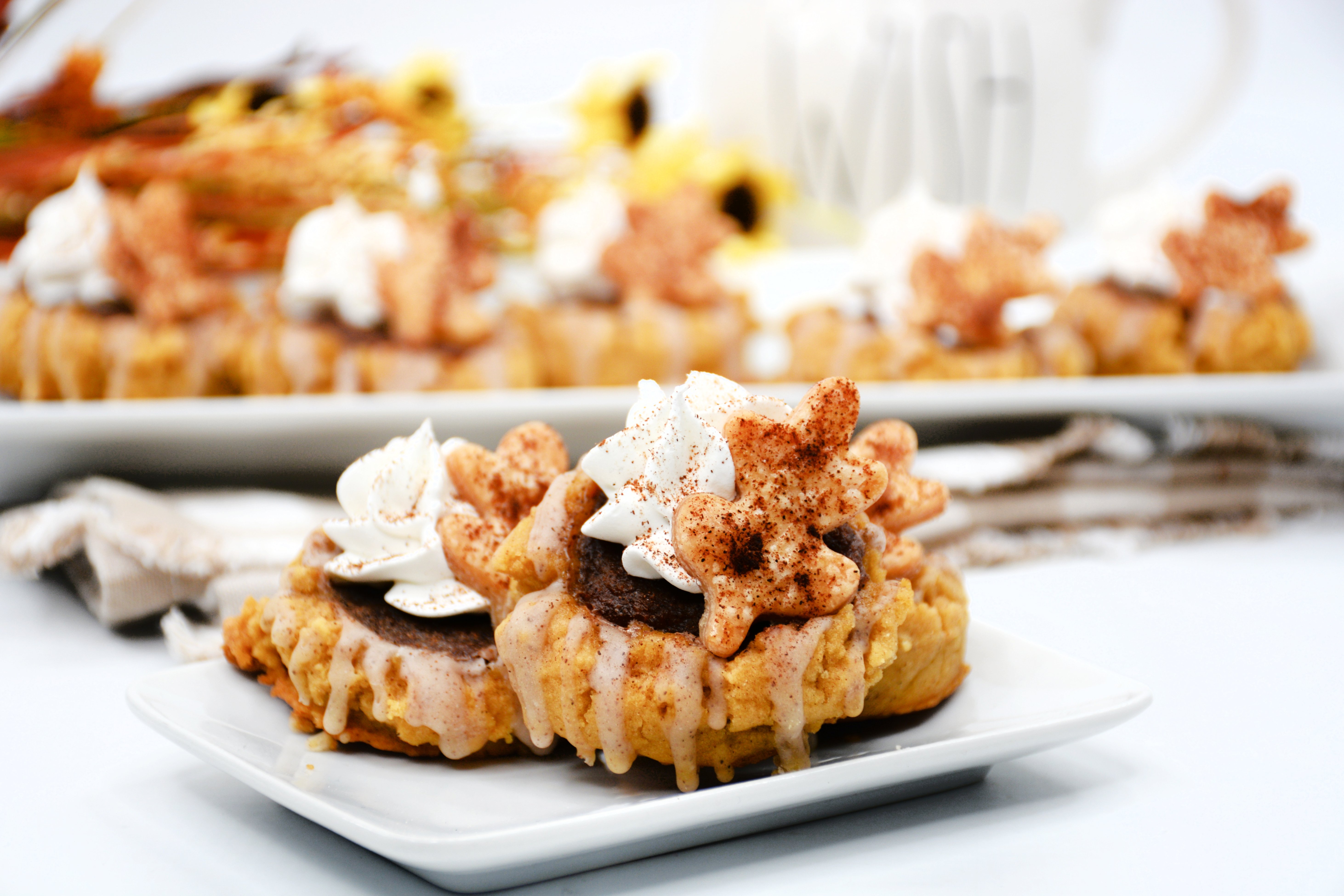 Horizontal image of three pumpkin pie cookies on a white plate topped with whipped cream