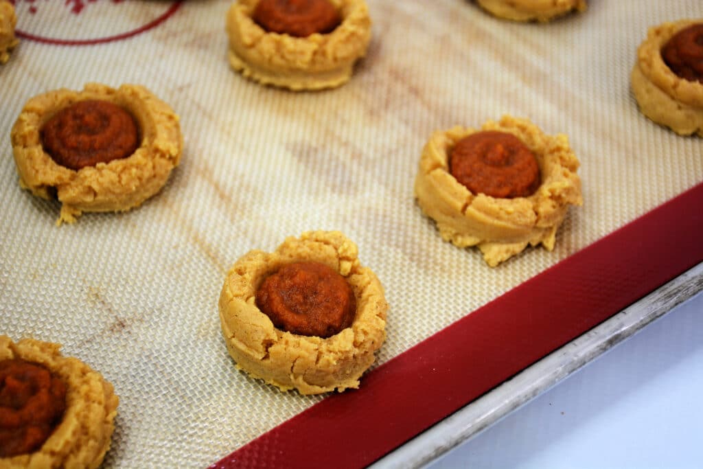 Pumpkin pie cookie dough on a baking sheet and filled with pumpkin pie filling