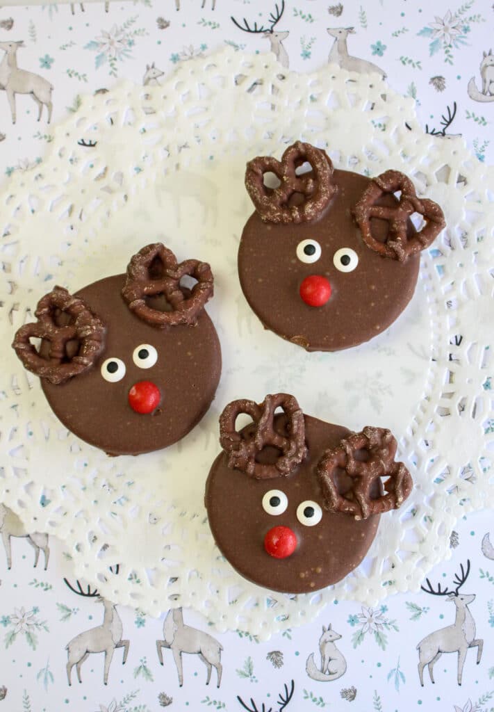 Three reindeer cookies on a white lace plate mat