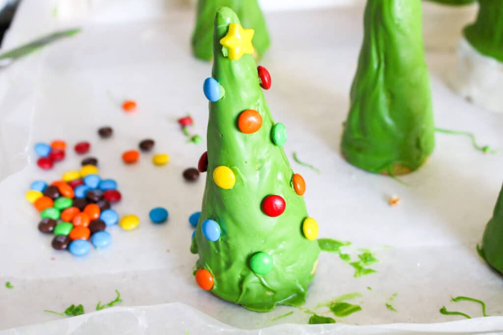 waffle cones dipped in green candy melts with mini m&ms on them