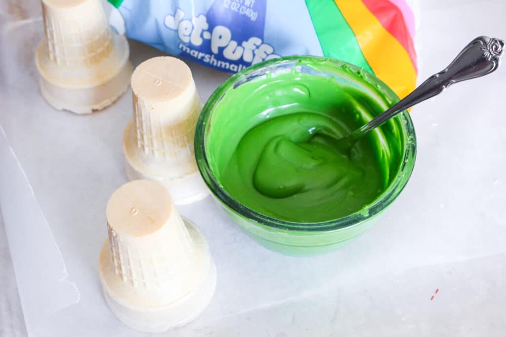 green candy melts melted in a glass bowl with ice cream cake cones