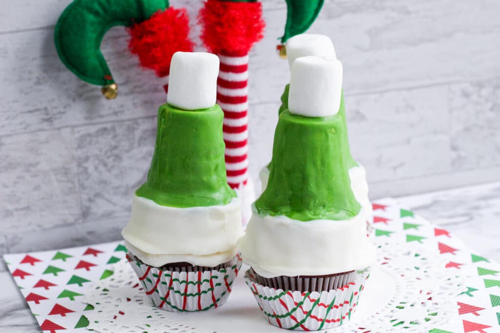 close up image of three elf hat cupcakes on a white table