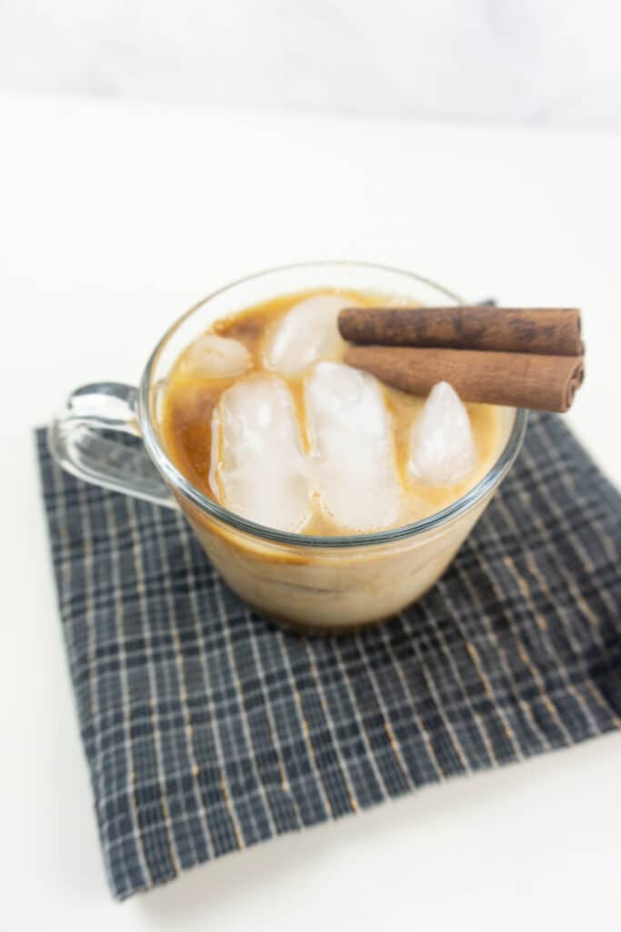 off center side view image of a clear mug of gingerbread white russian on a dark napkin