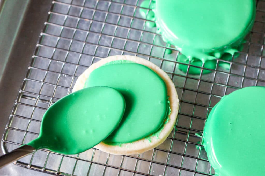 green frosting being pour into grinch cookies
