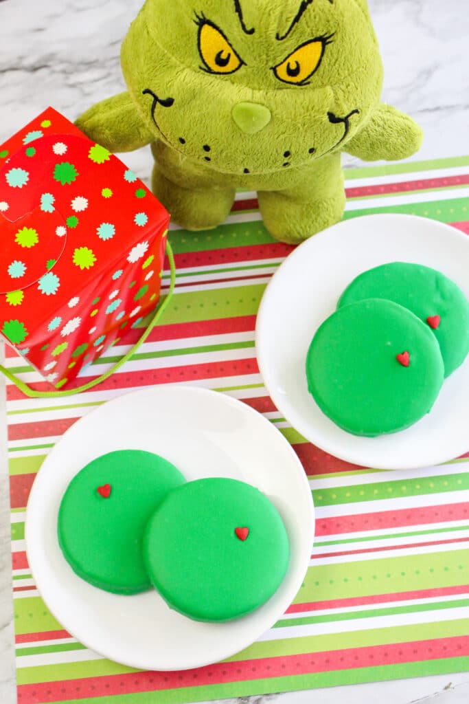 Four Grinch Cookies on two small round white plates
