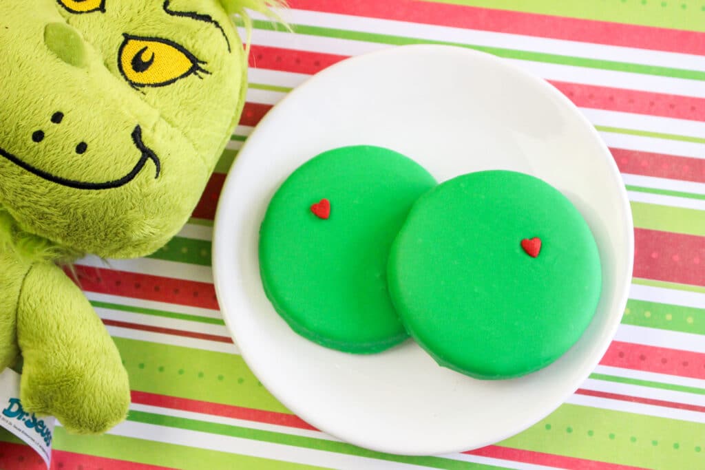 birds eye shot of two grinch cookies and a stuffed grinch on the left