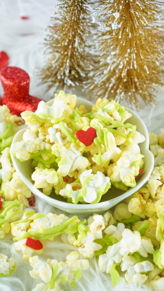 Bowl of Grinch Popcorn topped with red candy hearts