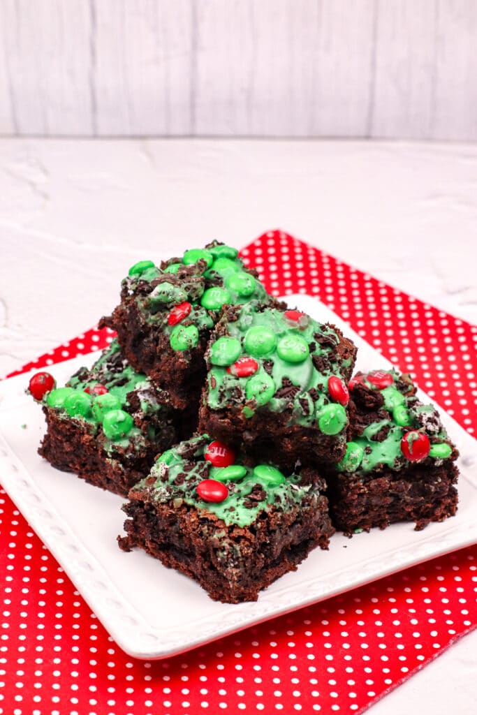 grinch brownies on a white plate on top of a red and white polka dot napkin