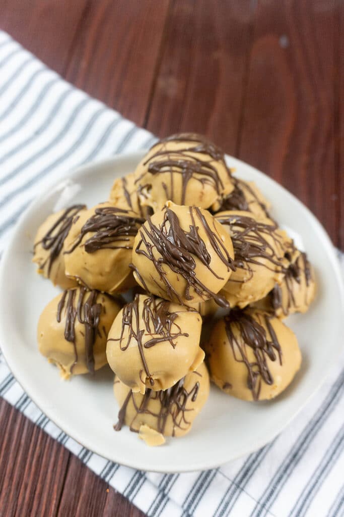 image of peanut butter truffles on a white plate on a cherry backdop