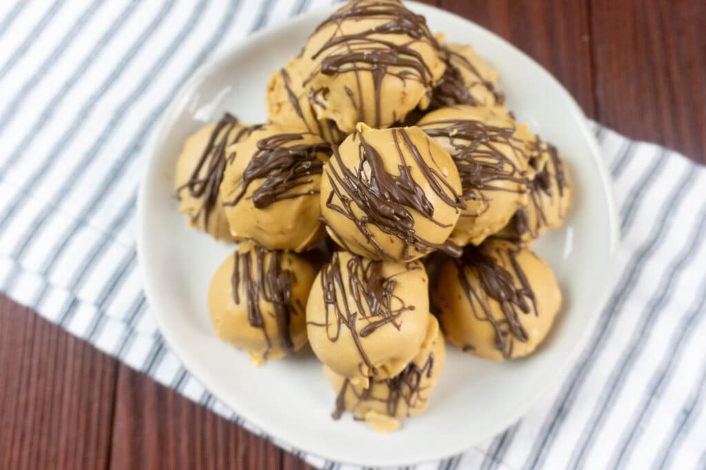 Peanut Butter Truffles drizzled with chocolate stacked on a white plate