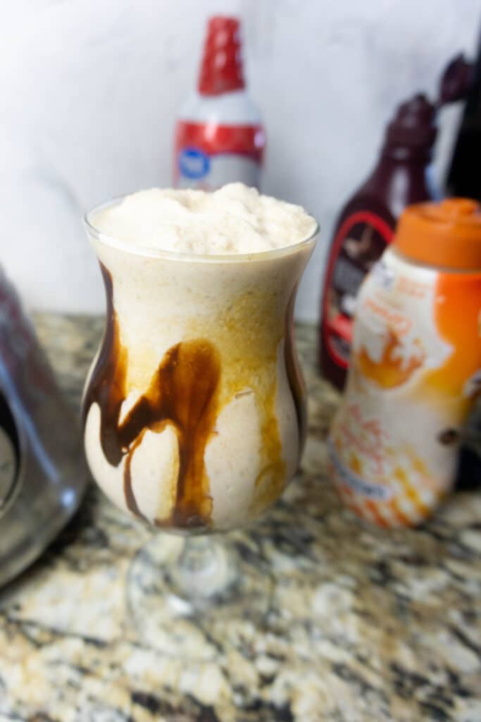 Peanut butter vwhisky in a milkshake glass with chocolate and caramel syrup