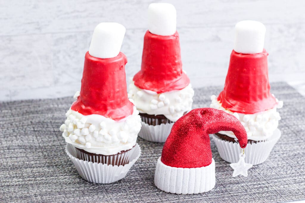 Three Santa Hat Cupcakes on a gray placemat