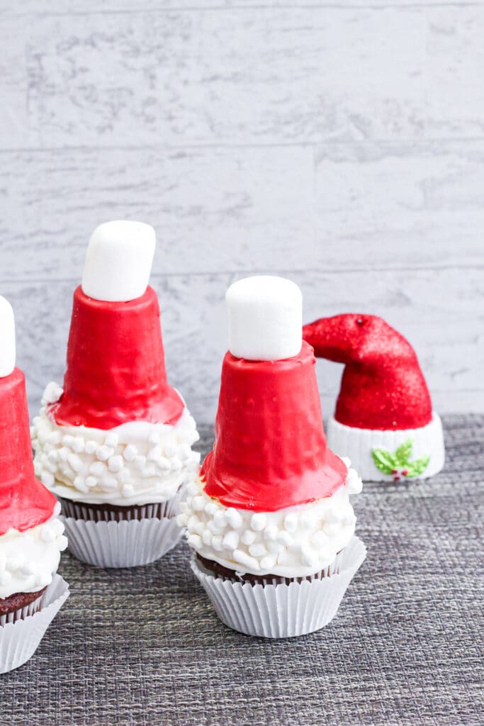 off center vertical image of three christmas santa hat cupcakes