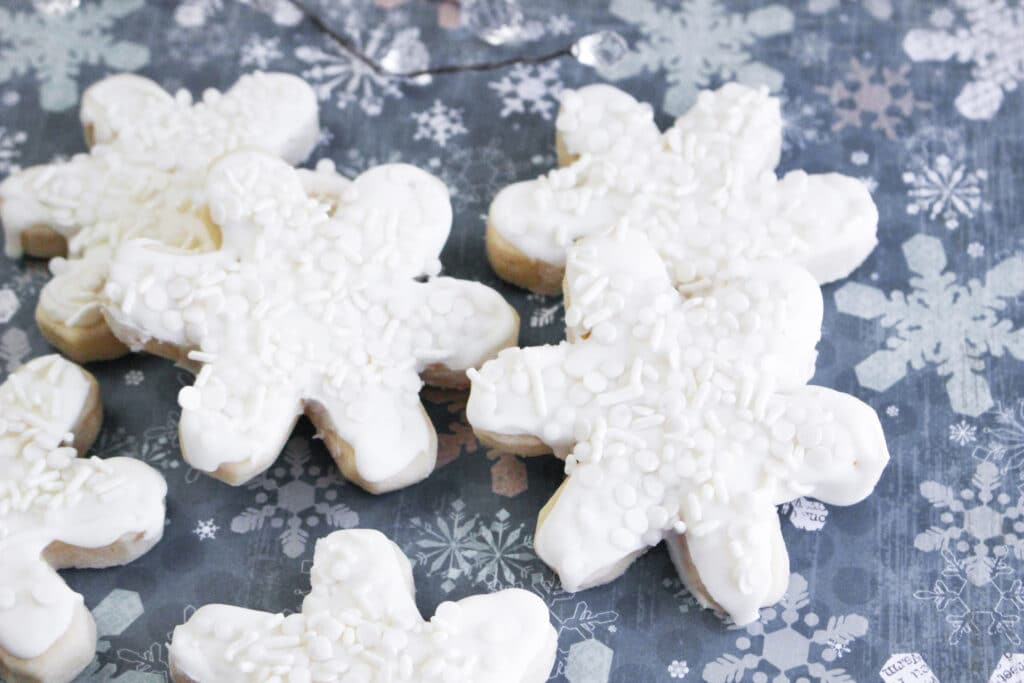 horizontal image of a six snowflake cookies on a table iwth a blueish gray backdrop