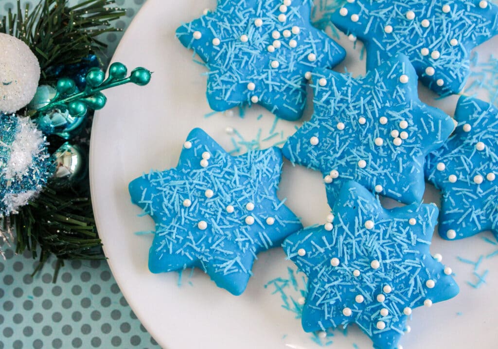 vertical image of blue star cookies with white sprinkles on a white plate