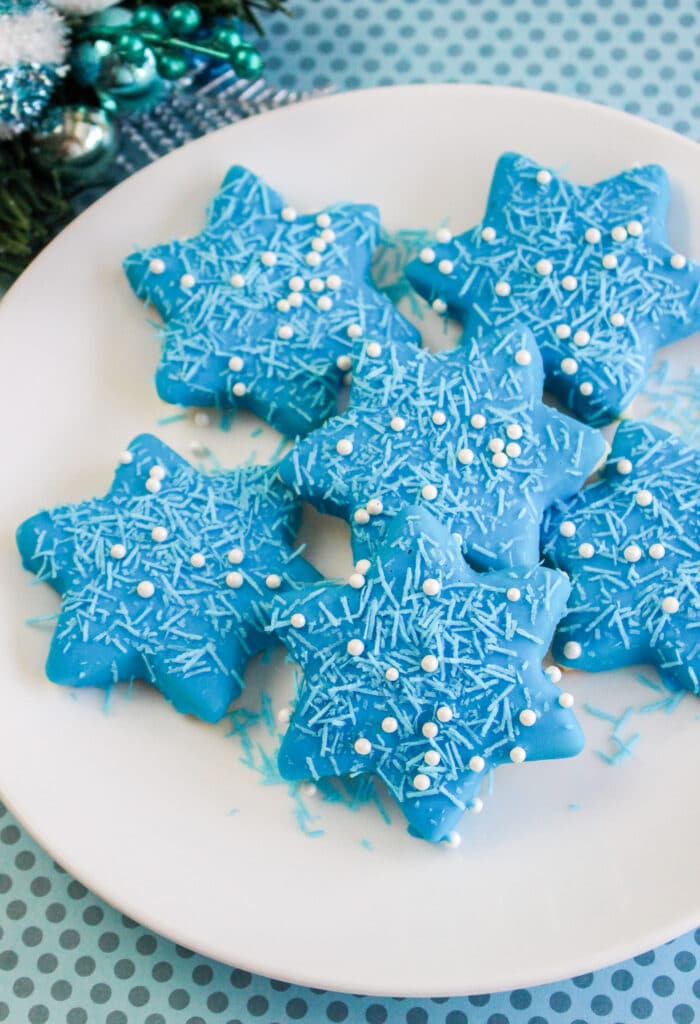 vertical image of blue star shaped cookies on a white plate