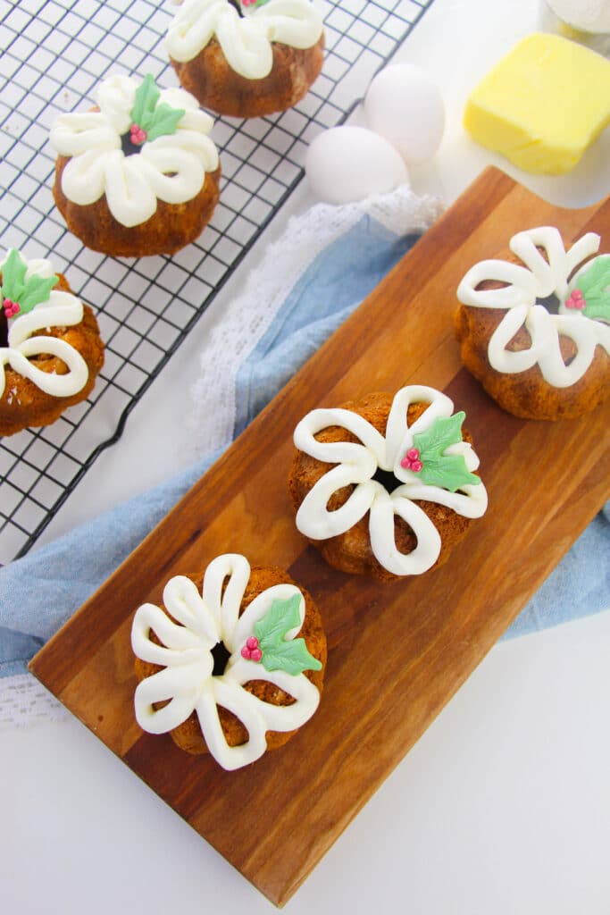 six mini bundt cakes on a wooden cutting board and a cooling rack