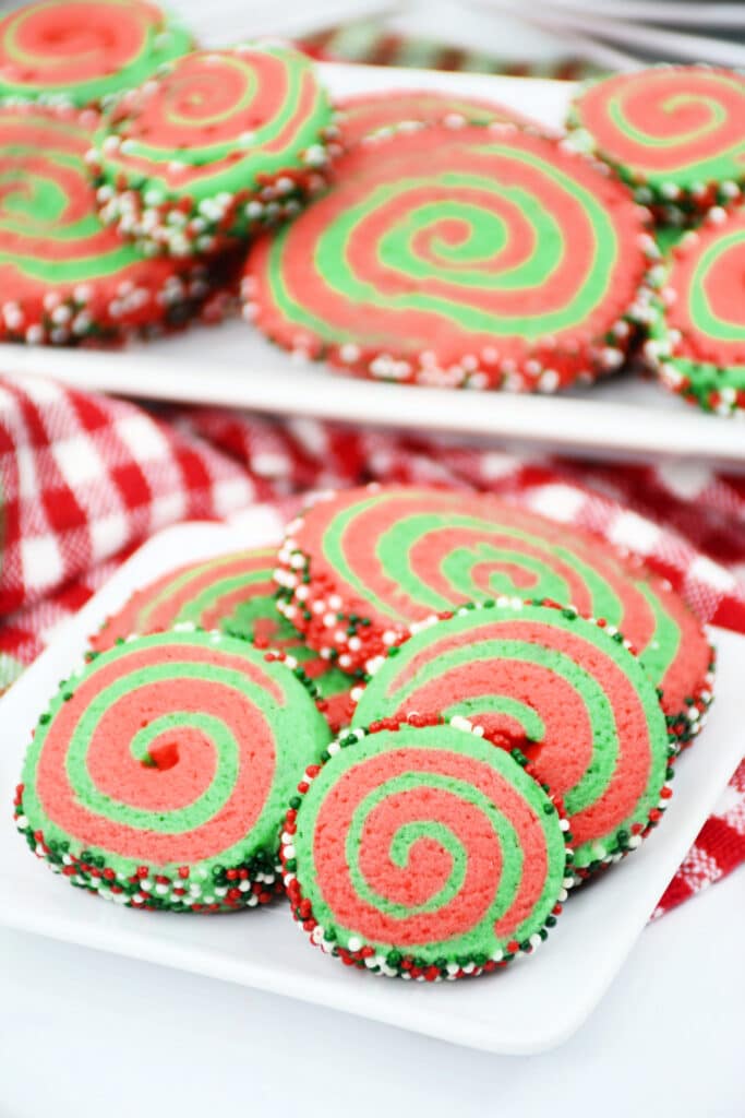 vertical image of a stack of christmas pinwheel cookies on a white plate