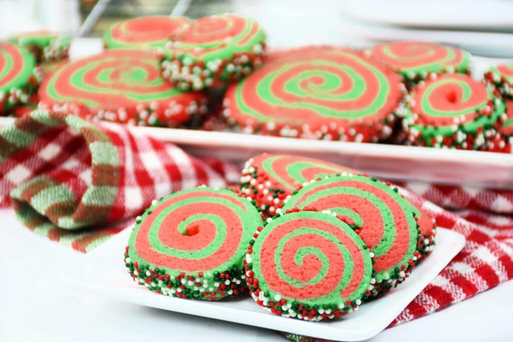 side view of a plate full of red and white christmas pinwheel cookies