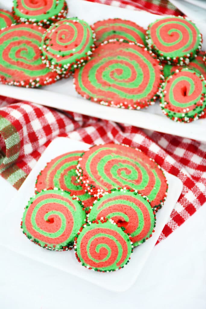 side angle birds eye image of a plate and platter filled with christmas pinwheel cookies