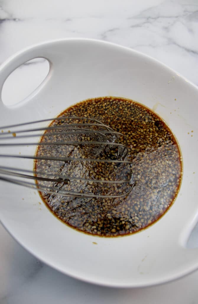 honey garlic soy marinade in a white mixing bowl with a whisk