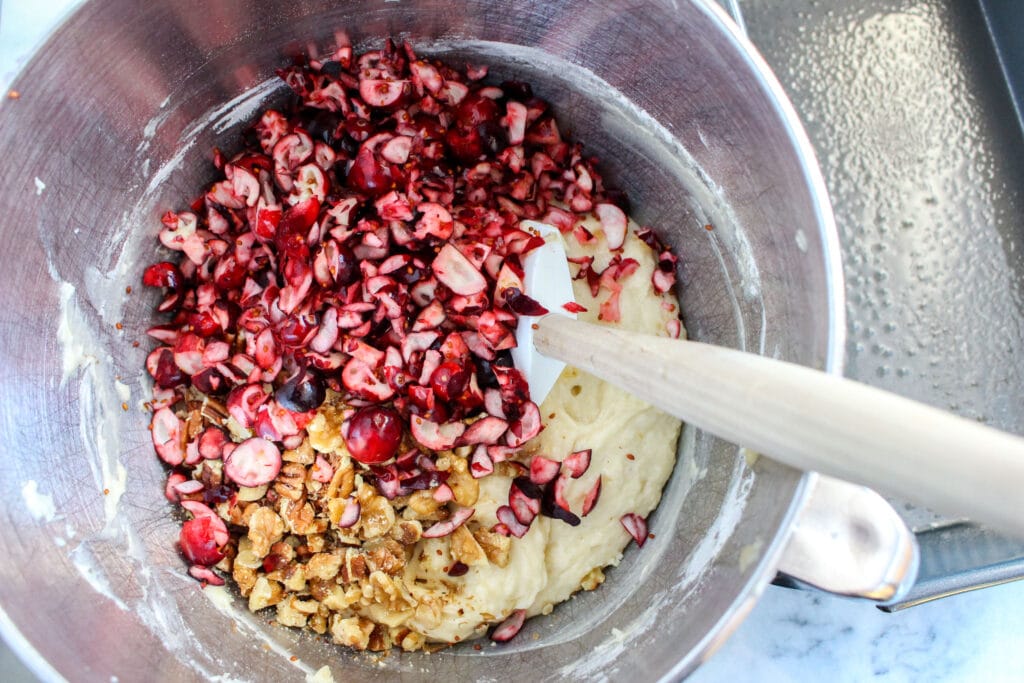 batter, walnuts and chopped cranberries in a sliver mixing bowl