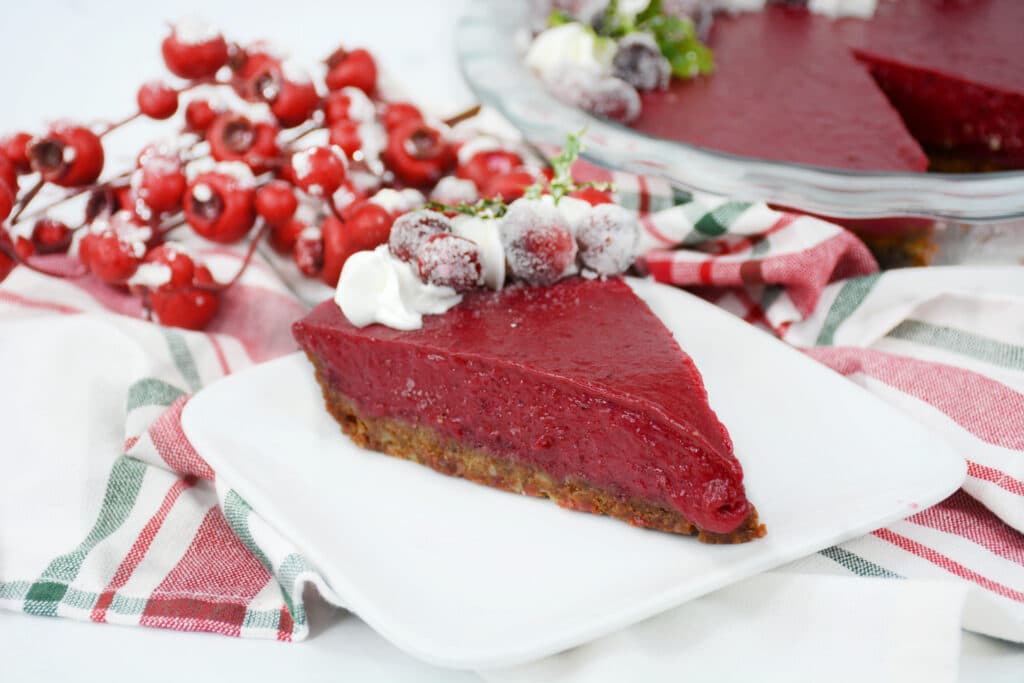 side view image of a slice of cranberry curd tart on a white plate