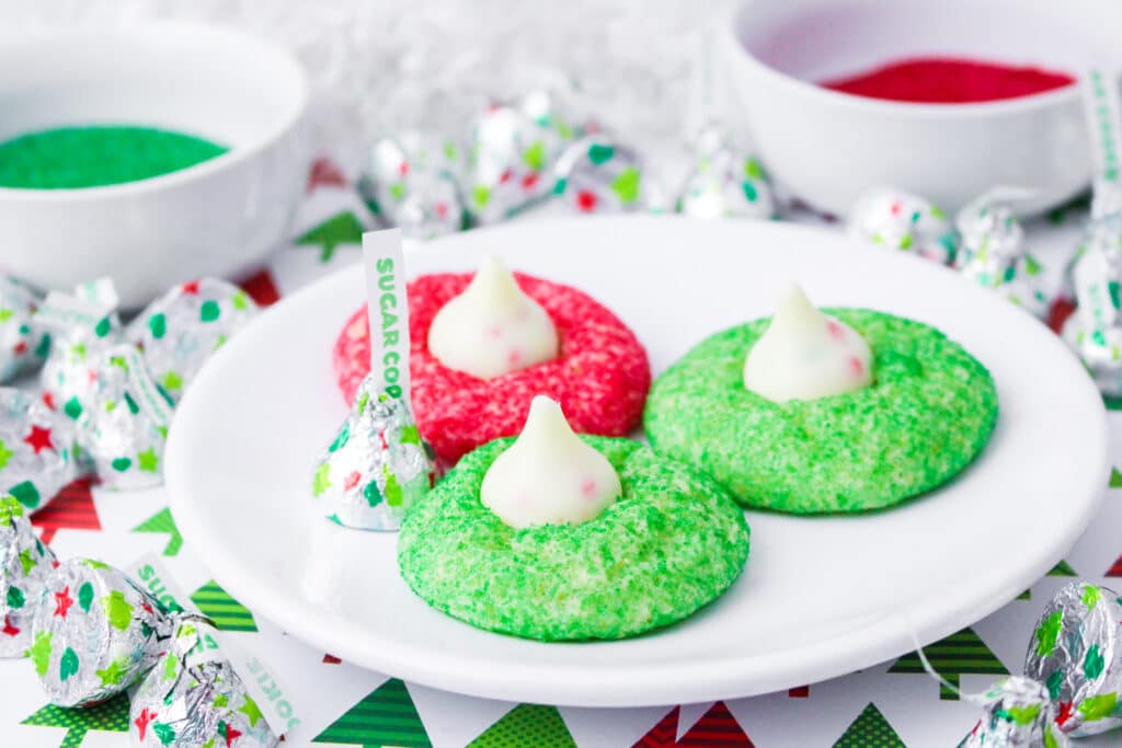 two green and one red hershey kiss sugar cookies on a white plate