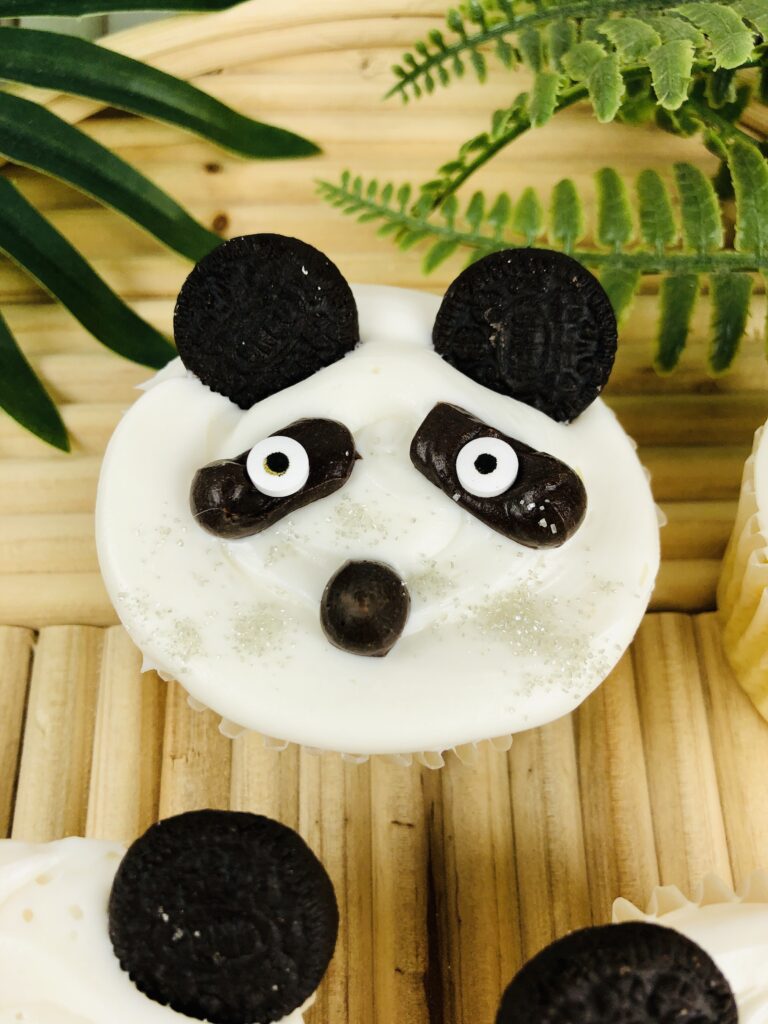 vertical image of a single panda cupcake on a bamboo tray