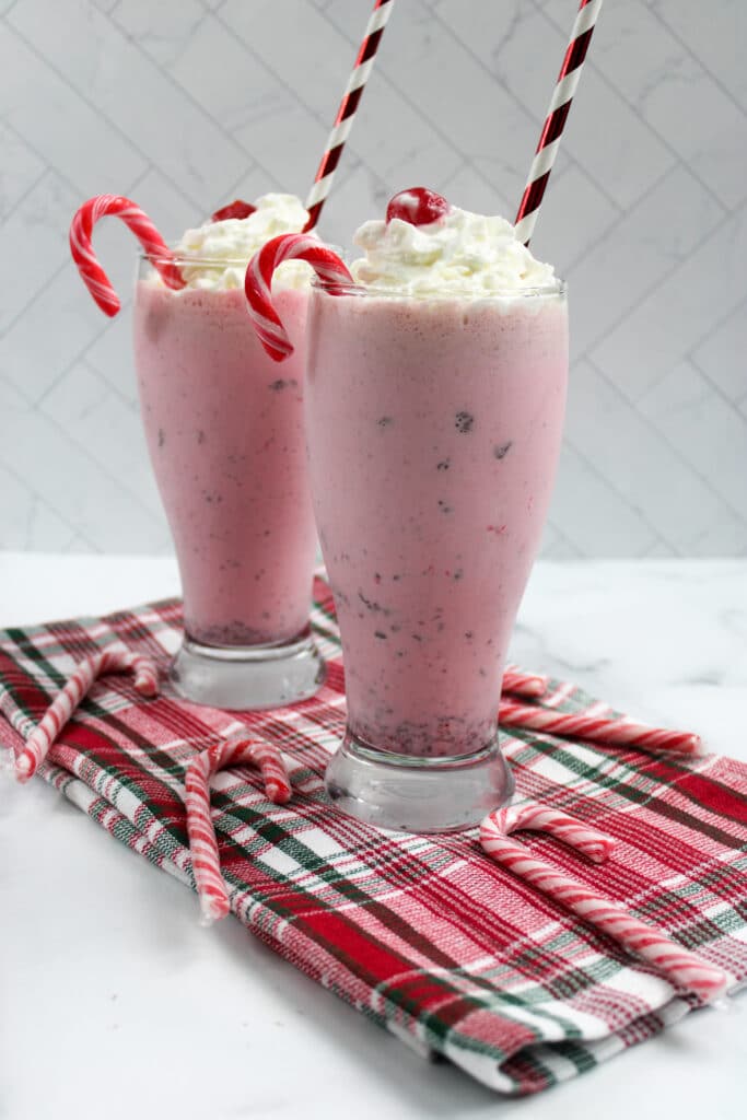 two peppermint milkshakes in a red and green striped napkin