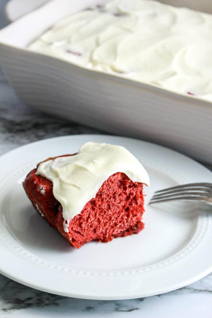 Red Velvet Cinnamon Rolls topped with cream cheese frosting on a white plate