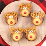 Square image of five rudolph cupcakes on a wooden round cutting board