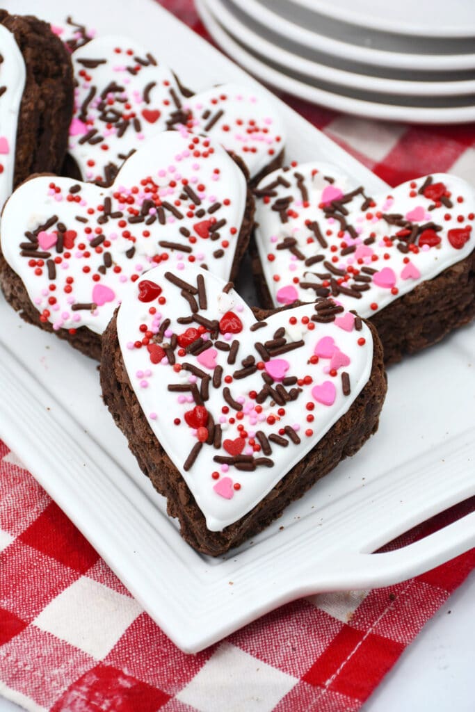 six heart shaped white chocolate brownies on a white platter