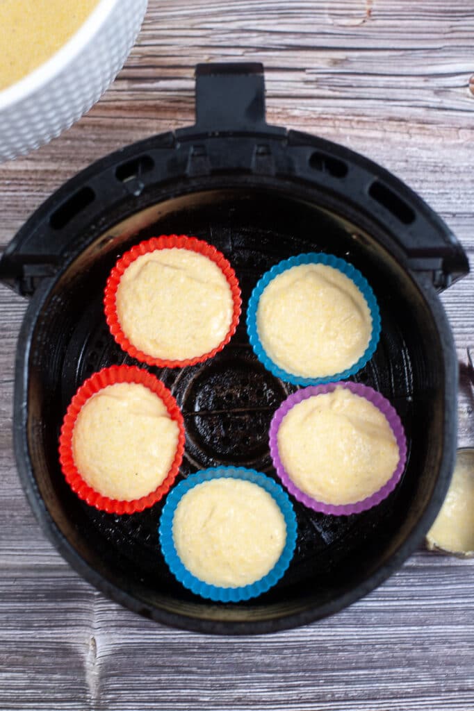 cupcake liners filled with air fryer cornbread batter in silicone muffin liners in an air fryer