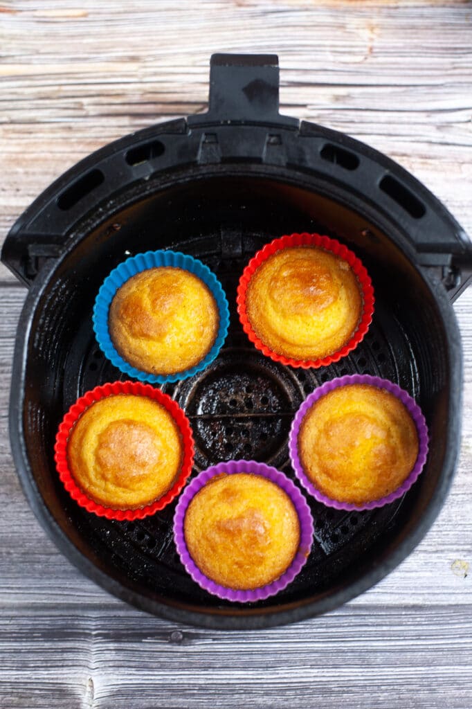 Cooked cornbread muffins in an air fryer basket