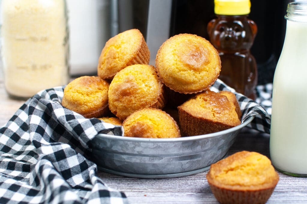 close up image of cornbread muffins with a honey bear in the background