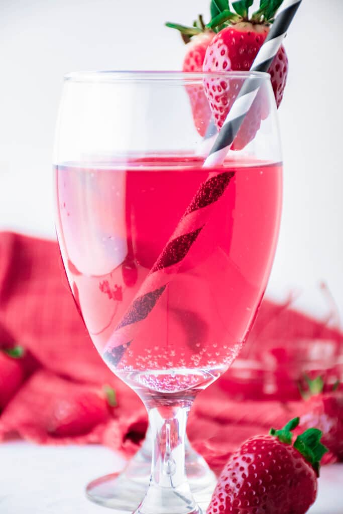 close up Cupid's Cocktail in a wine glass with a strawberry on the rim