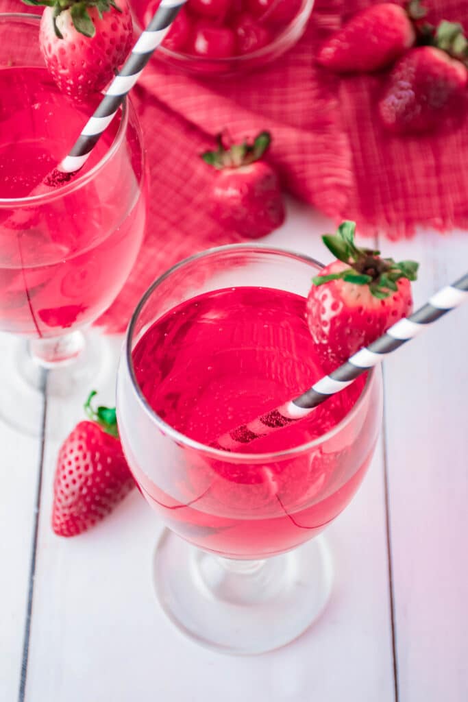 birds eye image of two glasses of Cupid's Cocktail in a wine glass with a strawberry on the rim