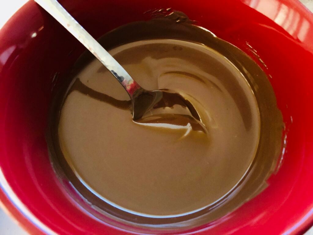 melted chocolate almond bark in a red mixing bowl