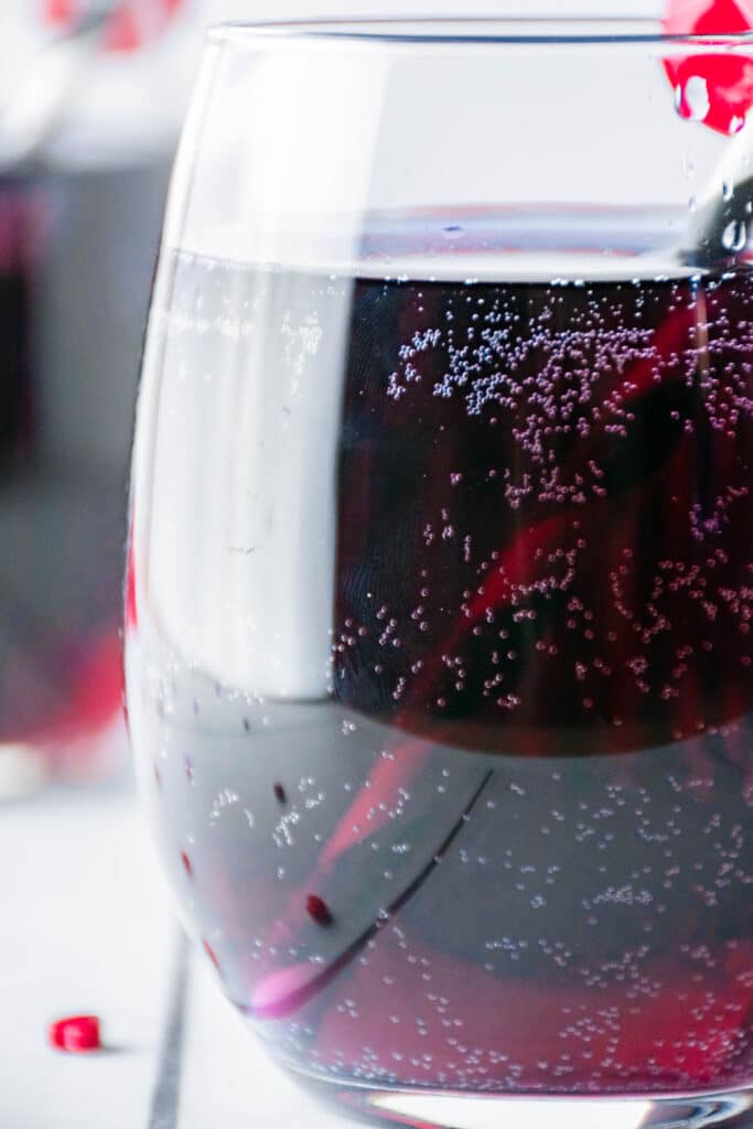 off center image of glass of love potion with a black and white straw a cherry on the rim