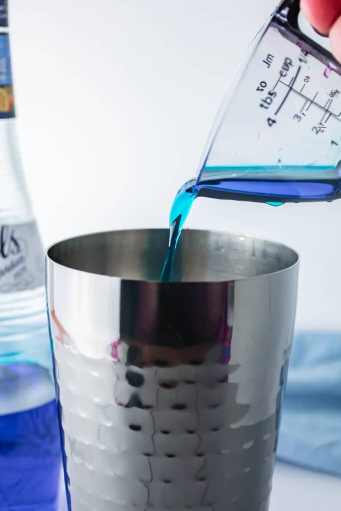 blue curacao being poured into a shaker