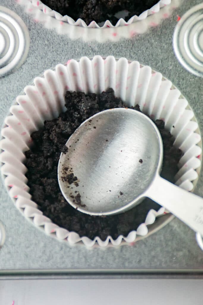 oreo crust being pressed into a cupcake liner